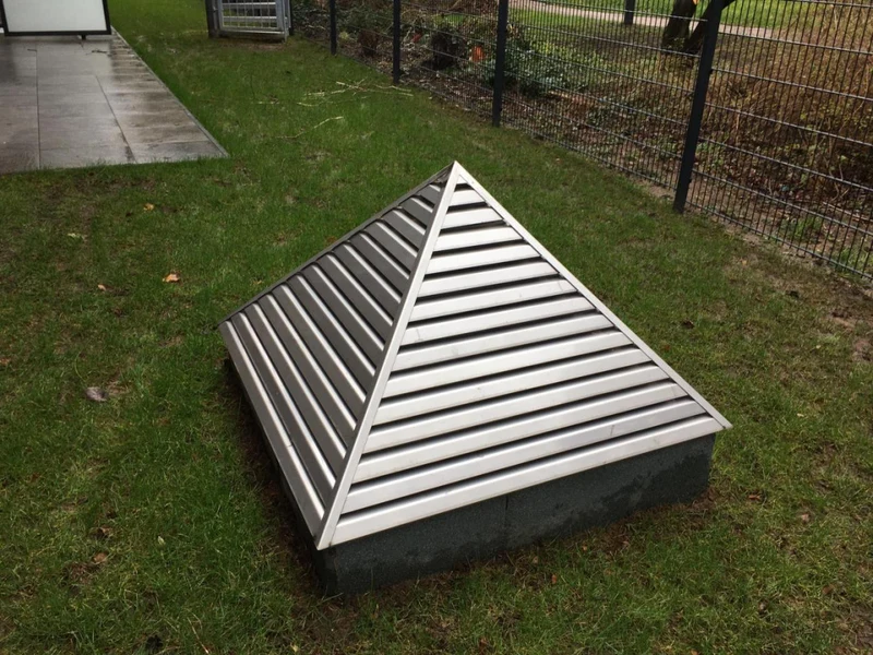 Fertige pyramidenförmige Metallkonstruktion mit Lamellen auf einem niedrigen Sockel